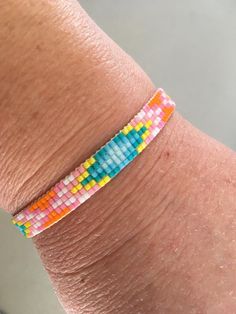 A fresh, citrus woven bracelet! I used 11/0 Japanese Miyuki Delica beads, which are known for their uniform shape, brilliance and high quality. The bracelet is finished with a heavy-duty bar clasp (shiny silver), a lobster claw and double ring. Bead colours: white, yellow, orange, 2 shades of pink and 3 shades of blue. It'll be a perfect fit if your wrist is 6.5 inches. I can add chain links if necessary. The bracelet width is approximately 0.8 cm, with 5-bead rows. My store: www.almasurfside.etsy.com Facebook: www.facebook.com/almasurfside YouTube: https://www.youtube.com/@almasurfside-surfandbeachj1170 Thanks for shopping at Alma Surfside! As a jewelry designer, I'm inspired by resort fashion and breezy California style. Having lived on the West Coast, my accessories are all about coasta Yellow Friendship Bracelets With Tiny Beads, Beaded Bangle Bracelets For Friendship, Yellow Bracelets With Tiny Beads For Friendship, Adjustable Jubilee Cuff Bracelet With Round Beads, Adjustable Beaded Cuff Bracelet For Friendship, Friendship Tiny Beads Stretch Bracelet, Multicolor Jubilee Beaded Bracelets For Friendship, Adjustable Beaded Bangle Bracelet, Beaded Bracelet Wristband For Friendship