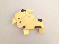 an origami cow with black spots on it's face