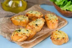 small muffins with cheese and spinach on a cutting board next to a bowl of lettuce