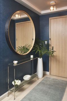 a bathroom with blue walls and a large round mirror on the wall next to a potted plant