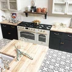 a kitchen with black and white tile floors and wooden counter tops, an oven and sink