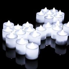 many lit candles are arranged in the shape of a heart on a black background with reflections