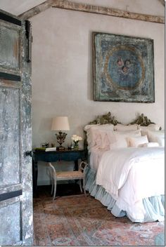 a bed sitting in a bedroom next to a painting on the wall over a doorway