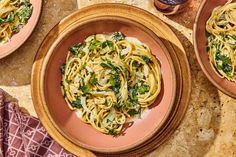 two plates of pasta with spinach and cheese on the side, next to a bottle of wine