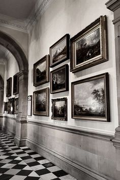 black and white photograph of paintings on the wall in an old building with checkered floor