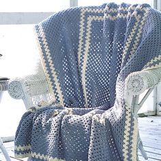 a rocking chair covered in a blue and white crochet blanket on a porch