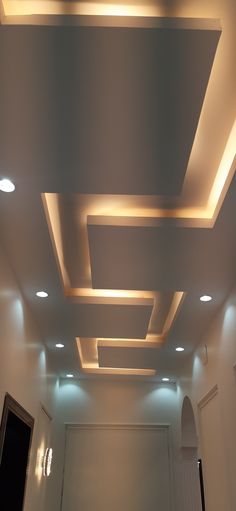 an empty room with white walls and lights on the ceiling is lit by recessed lighting