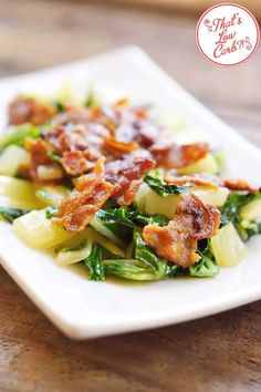 a white plate topped with broccoli and bacon on top of a wooden table