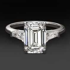 an emerald - cut diamond ring with baguets on the shoulders and side stones