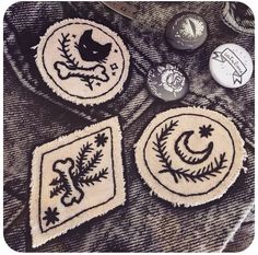 three embroidered patches sitting on top of a table next to buttons and other things in the background