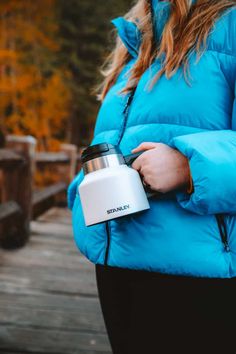 a woman in a blue jacket holding a coffee mug