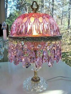 a pink chandelier sitting on top of a white table next to a window