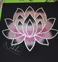 a large pink and white flower is on a black board with glitters in it