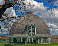 a green and white barn with a large round roof