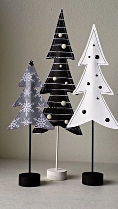 three paper christmas trees sitting on top of a white table next to black and white decorations