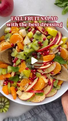 a white bowl filled with fruit and topped with a wooden spoon