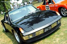 an orange and black car parked next to each other on top of a grass covered field