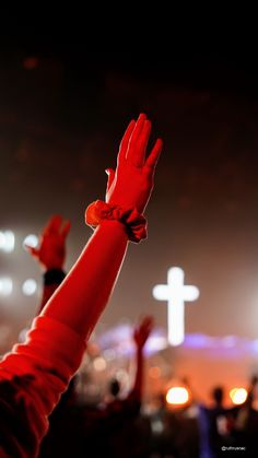 a person holding their hands up in the air at night with other people behind them