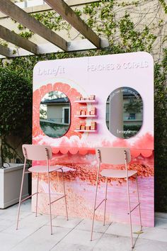 two chairs sitting in front of a pink counter with mirrors on it's sides