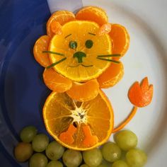 an animal made out of oranges and grapes on a plate with the face of a lion