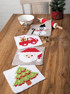 three crocheted christmas coasters sitting on top of a wooden table next to a bowl