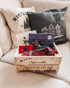 a wooden box filled with christmas gifts sitting on top of a couch next to pillows