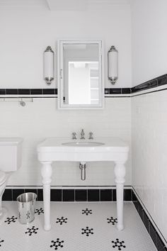 a bathroom with black and white tile flooring next to a sink, toilet and mirror