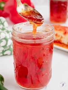 a spoon full of ketchup sitting on top of a jar filled with pizza sauce