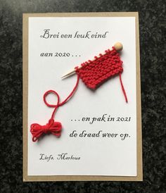 a red knitted object with a wooden button on it's end is shown in front of a card