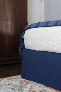 a bed with blue and white bedspread on it in front of a closet