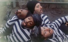 three men in striped shirts laying on the ground with their heads wrapped around each other