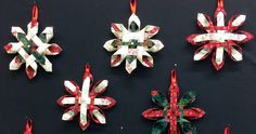 six paper snowflakes are hanging on a black wall with red and green ribbons