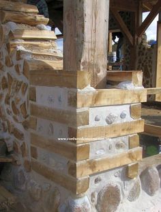 a close up of a brick wall made from wood and stone with rocks around it