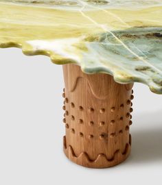 a close up of a wooden table with green and yellow designs on the top,