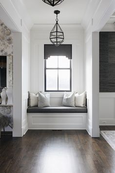 a window seat in the corner of a room with wood flooring and white walls