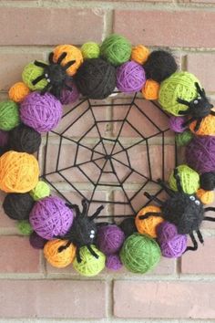 a wreath made out of balls of yarn and crocheted spider webs on a brick wall