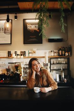 a woman sitting at a bar talking on her cell phone and holding a coffee cup