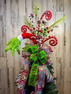 a christmas tree decorated with candy canes and bows on top of a wooden wall