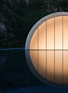 a circular light fixture sitting on top of a black surface next to a mountain range