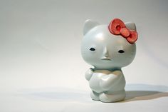 a white cat figurine with a red bow on it's head sitting in front of a white background