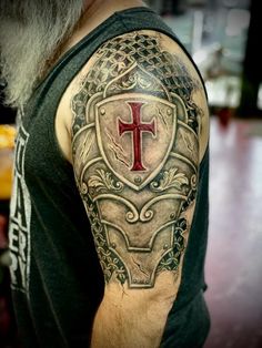 a man with a cross and shield tattoo on his arm