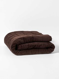 two blankets folded on top of each other in dark brown velvets, against a white background