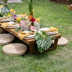 a table set up with plates and place settings on the grass for an outdoor meal