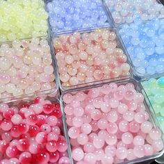 there are many different colors of beads in the trays on the table with each other