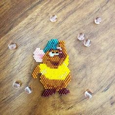 a beaded toy is sitting on a wooden table with ice cubes around it