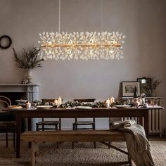 a dining room table and bench with candles on the top, surrounded by greenery