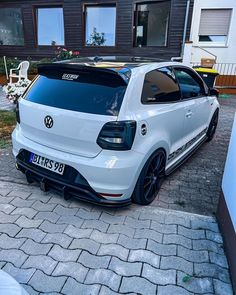 a white volkswagen car parked in front of a house