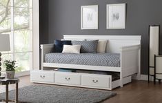 a white daybed with drawers underneath it in a living room next to a window