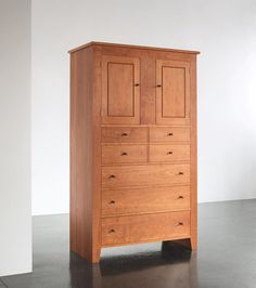 a tall wooden dresser sitting on top of a black floor next to a white wall