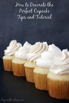 several cupcakes with white frosting are lined up